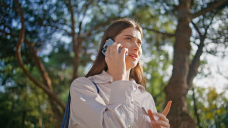 woman engaged phone conversation walking sunny green park closeup. lady talking