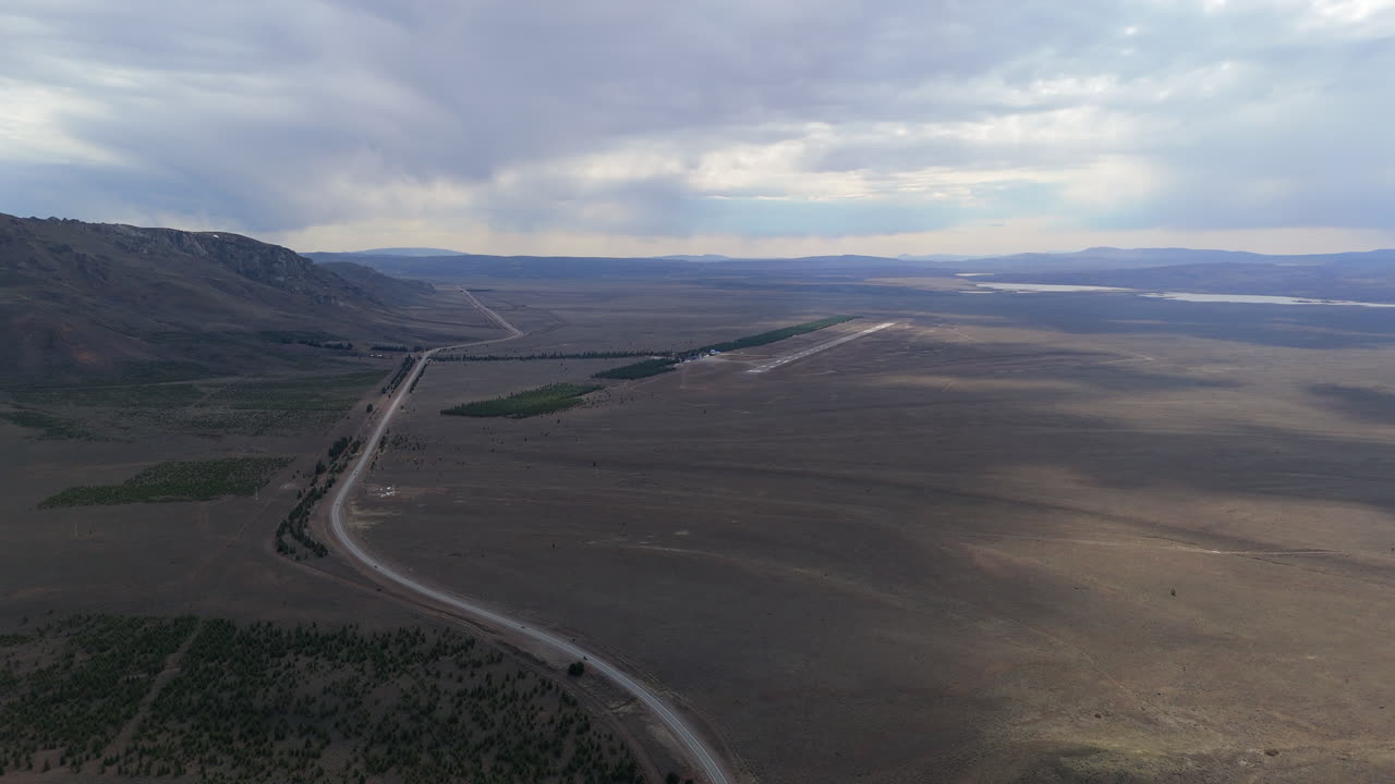 Capturing an aerial view of Brigadier Gral. Antonio Parodi airport near Esquel, Argentina, surrounded by the dramatic patagonian landscape and rugged terrain, drone flying forward slow motion