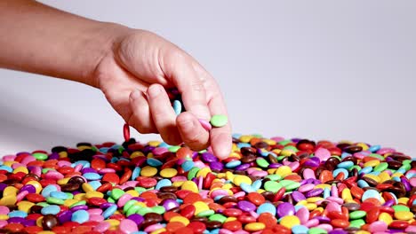 hand picking colorful candies from a pile