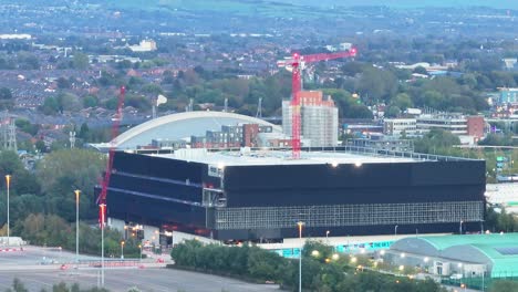 Co-op-Live-Tilt-up-drone-shot-of-buildings-in-Manchester-City-in-the-evening,-England,-Europe