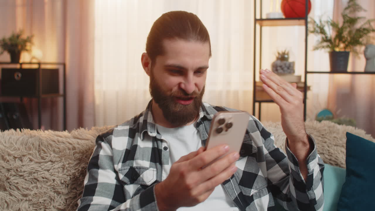 Young man paying with credit card at home phone purchase sofa check nod ok confident secure vibe