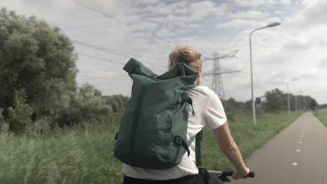 Un-Primer-Plano-De-Una-Mujer-Joven-En-Bicicleta-Por-La-Hermosa-Campiña-Holandesa,-Mirando-A-Izquierda-Y-Derecha