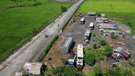 road through fields with abandoned old buses on the side near malilipot in albay, philippines. aerial drone shot