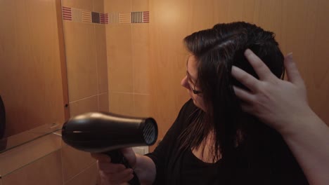 mujer joven dedo peinando el cabello mojado mientras se seca con secador de pelo, slowmo closeup