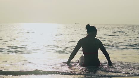 silhouette of slim woman sitting in ocean waves slow motion