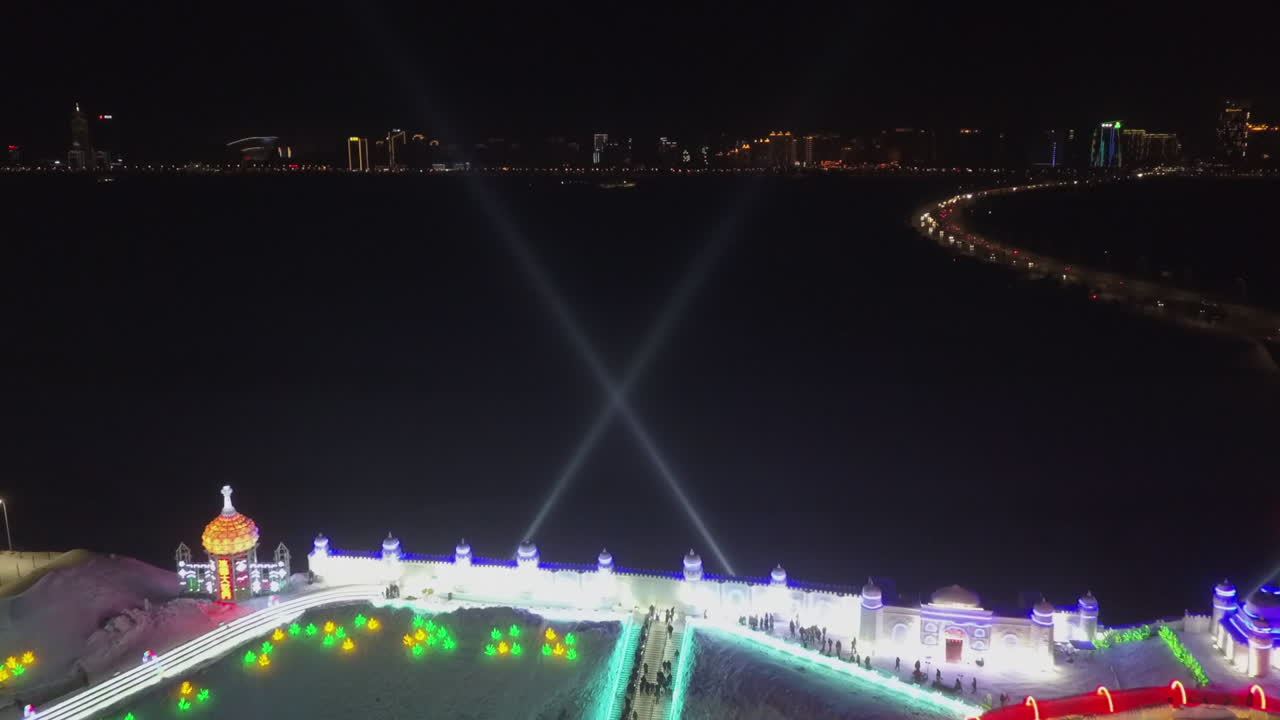 luces de búsqueda barren el cielo nocturno en el festival de hielo en harbin china, antena