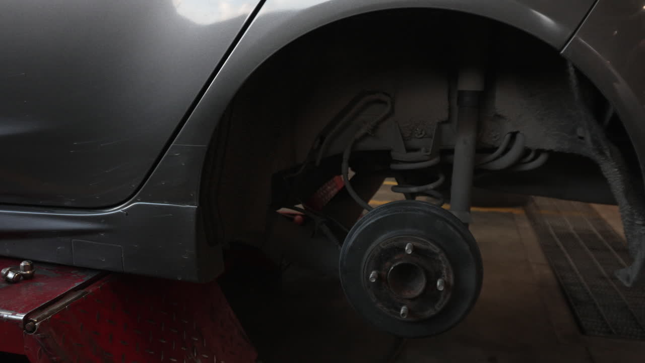 Gros plan d'un système de freinage de véhicule sur un cric, sans roues, dans un garage.