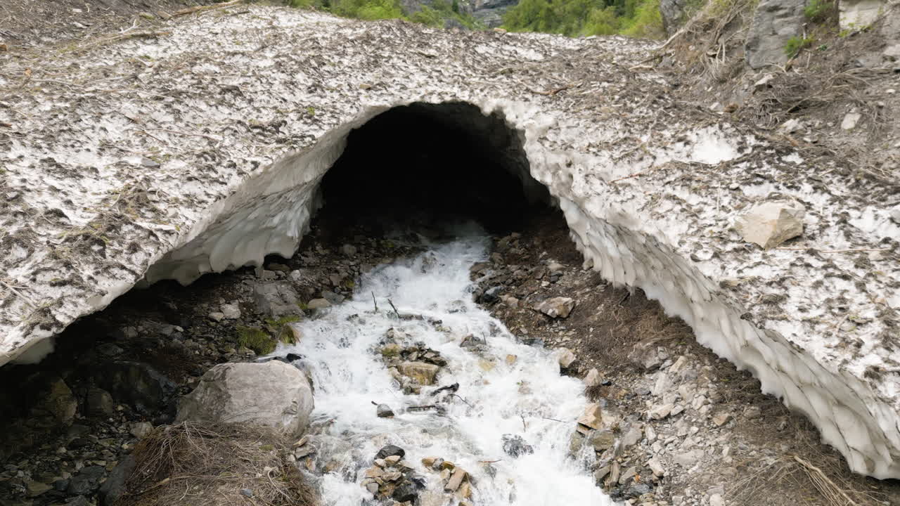 Aerial view across cascading ice cave stream water rushing from rocky tunnel entrance in Provo, Utah