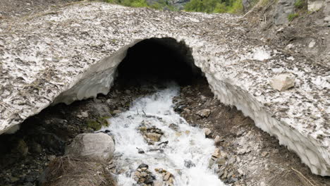 aerial view across cascading ice cave stream water rushing from rocky tunnel entrance in provo, utah