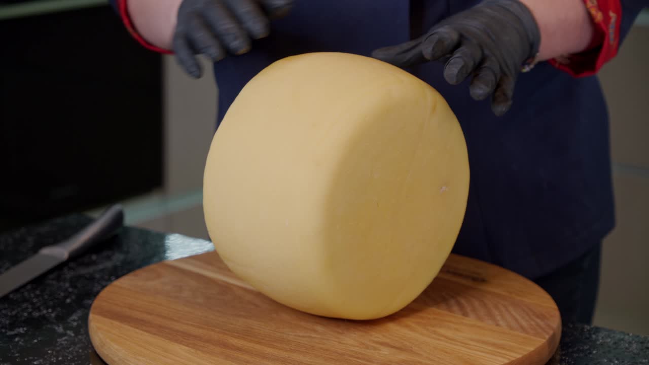un trabajador de una lechería de queso inspecciona el queso duro cocido. evalúa la calidad del producto antes de venderlo.