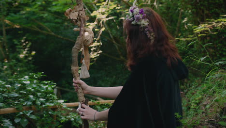 young-druid-girl-sitting-in-a-forest-contemplating-her-staff-medium-shot