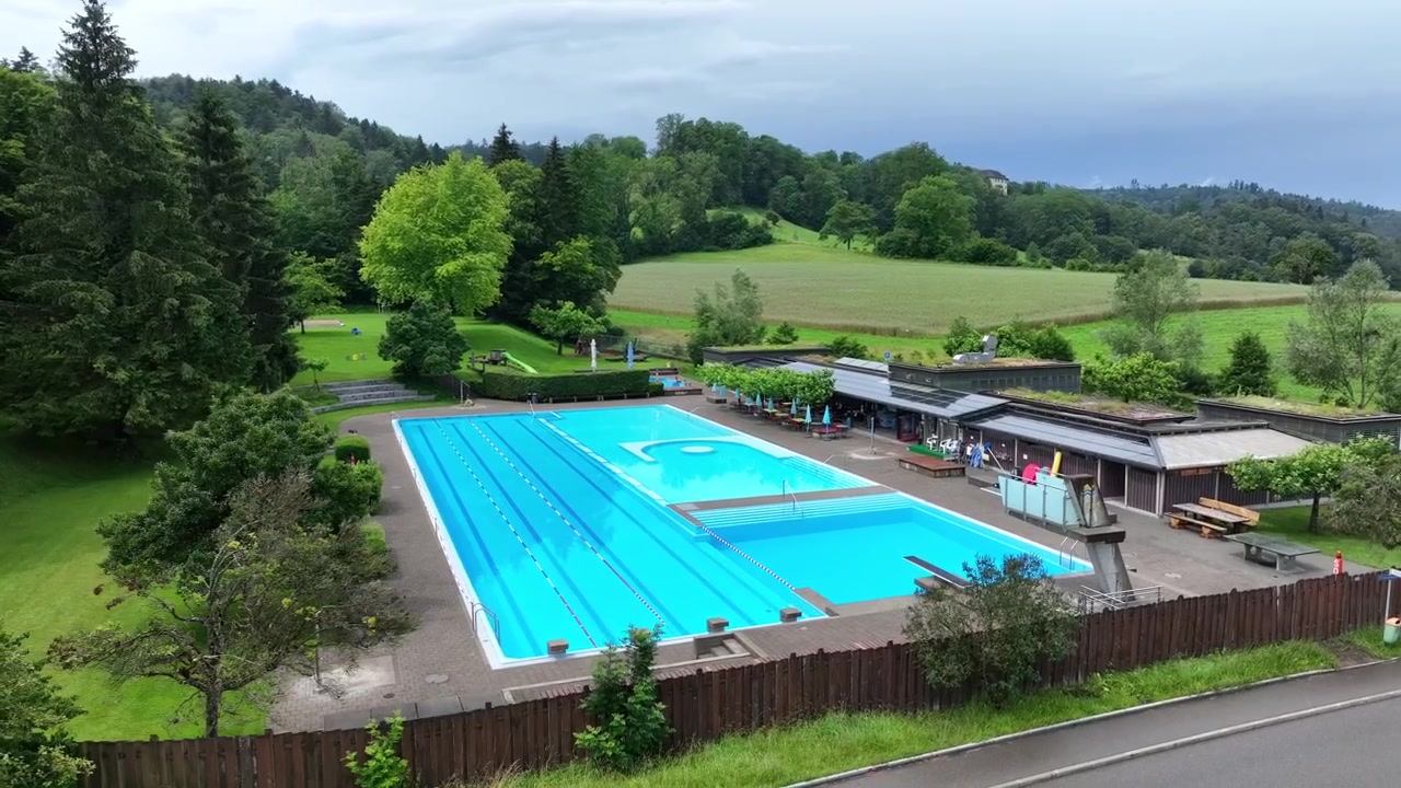 スイスの高級リゾートにある飛び込み台付きレジャースイミングプールを旋回する空撮