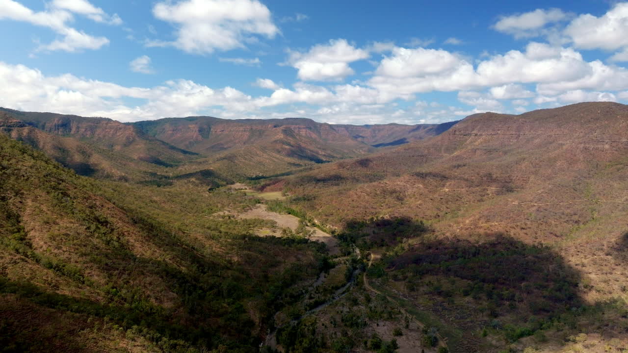 4k drone flyover paisaje rural natural australiano con montañas, matorrales y cielo nublado azul
