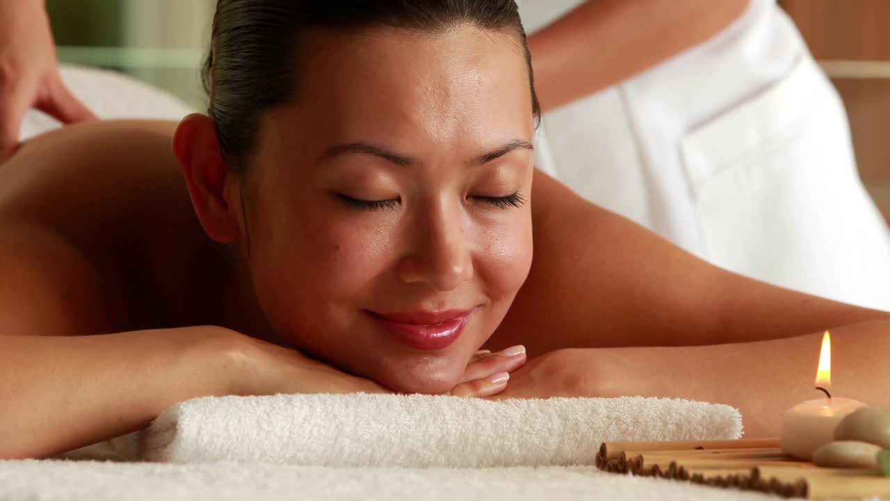 매력적인 갈색 여성이 마사지를 받고 있습니다.