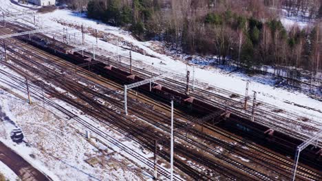 a long freight train of empty goods wagons in katowice poland - drone aerial reveal of surrounding countryside - cold snow covered landscape