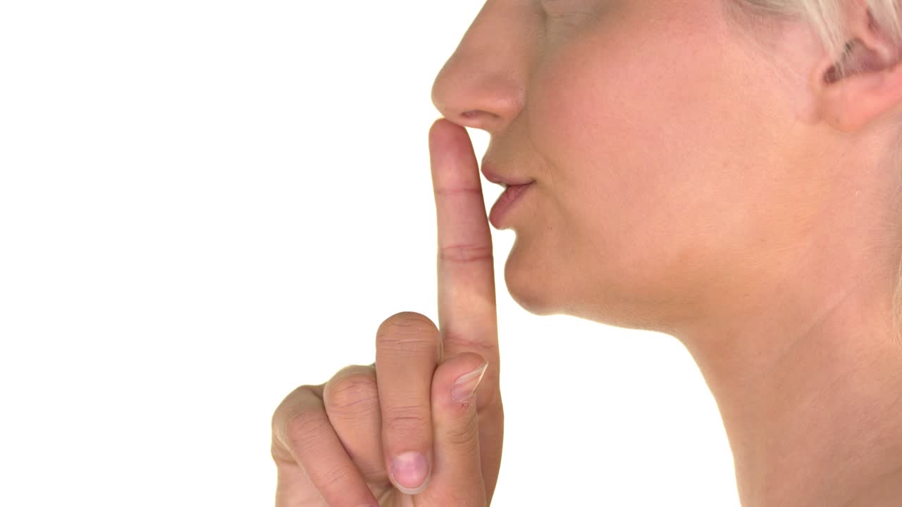 Closeup on lips of a young woman applying finger to lips - gesturing silence