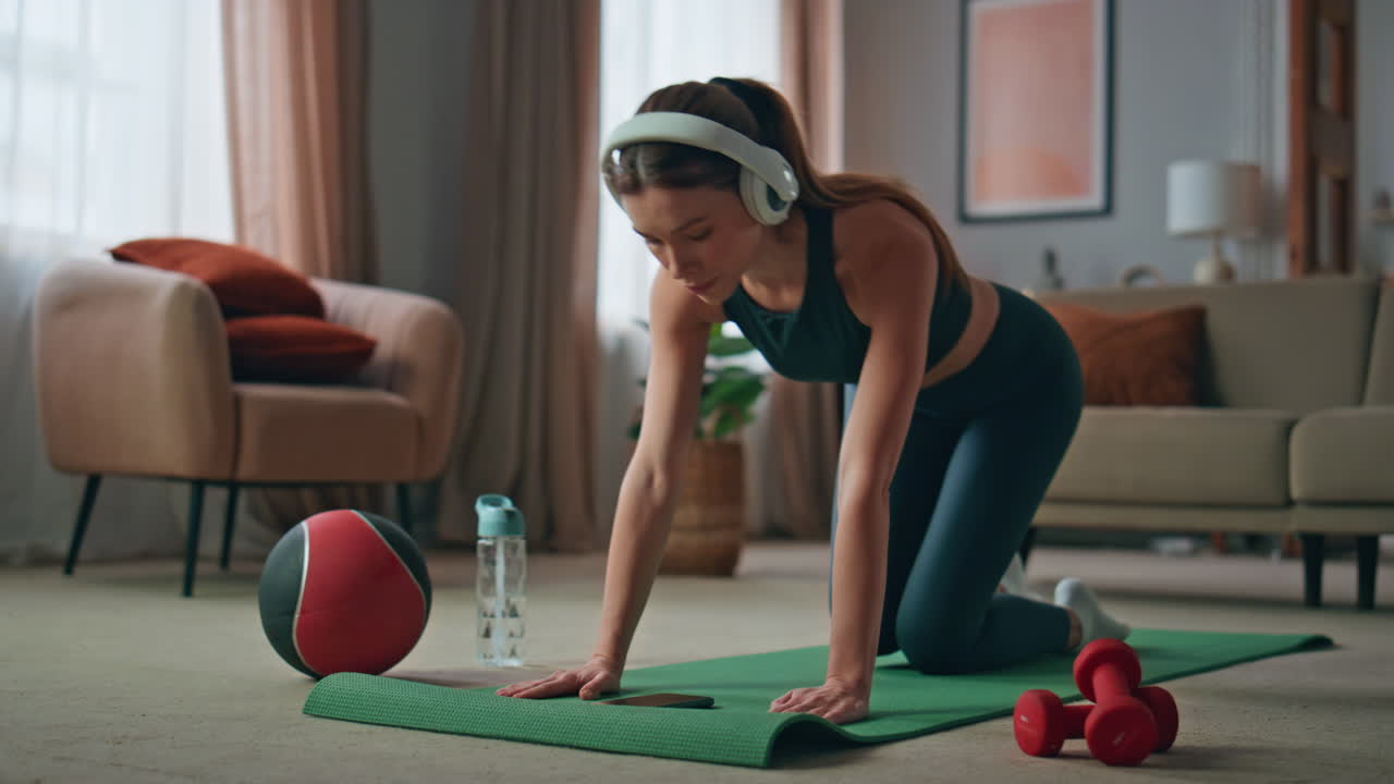 Girl making sport exercises in headphones at home workout. Woman stretching