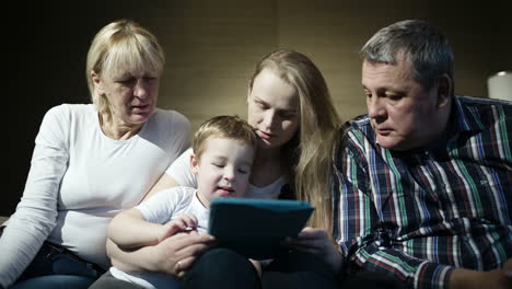 Family-watching-boy-playing-game-on-touchpad