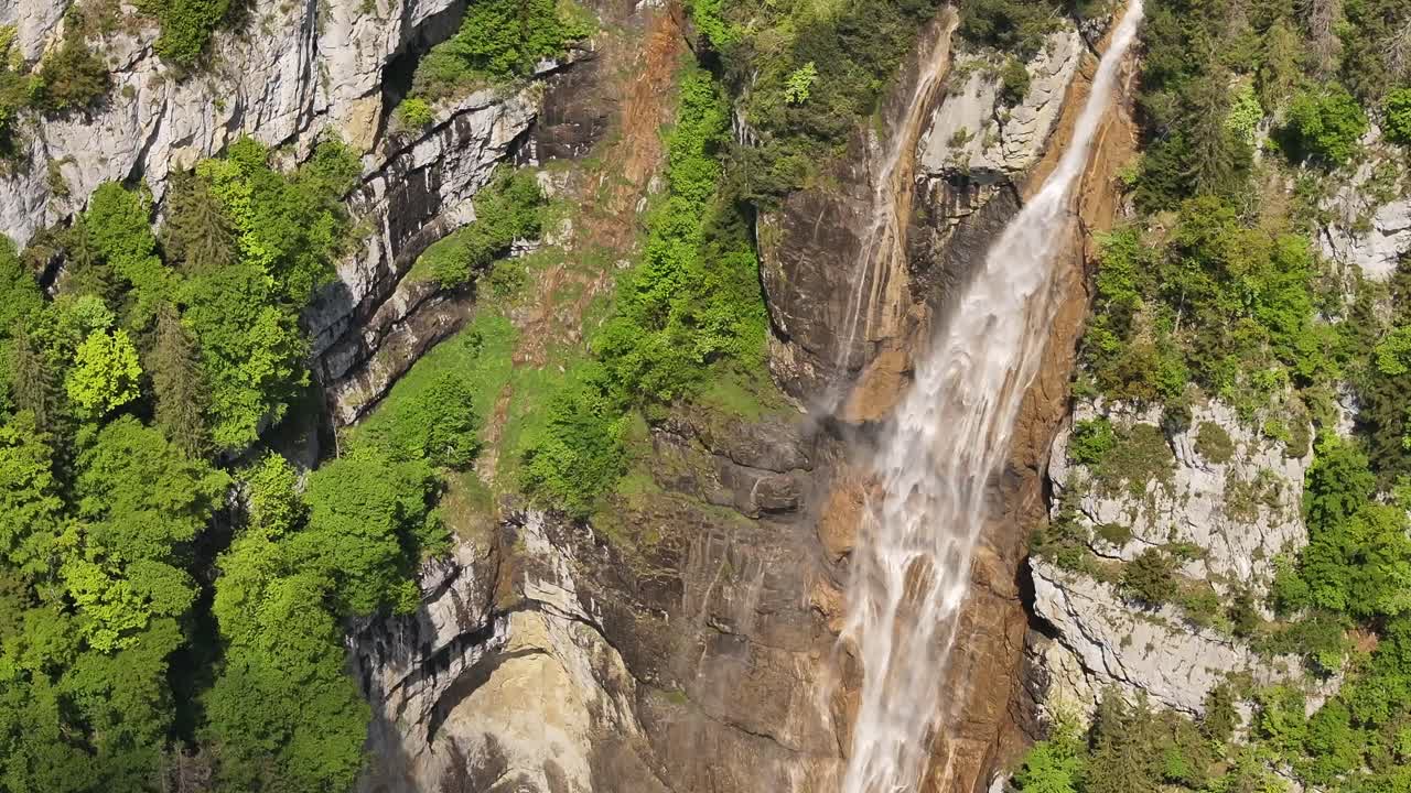 Seerenbach falls in Betlis, Switzerland aerial view, tall waterfall flows down lush cliffs, surrounded by greenery under clear skies