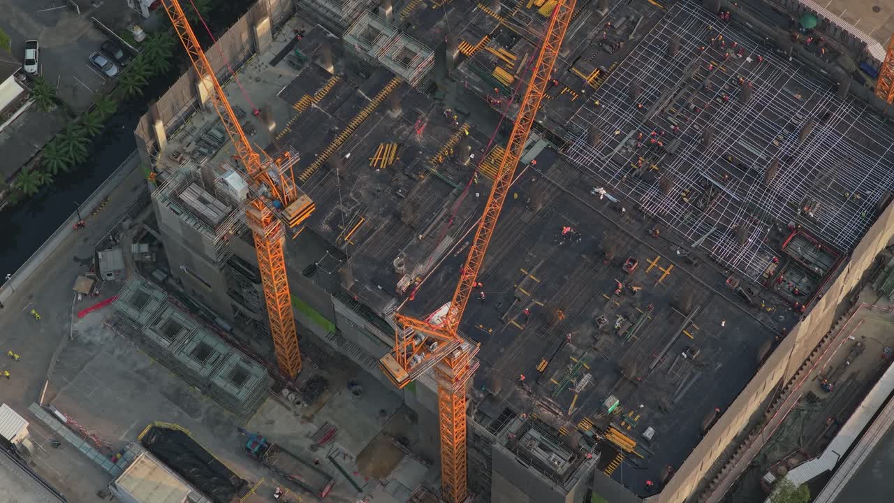 High angle view of a developing building project with tower cranes and engineers working on the concrete foundations and rebar framework