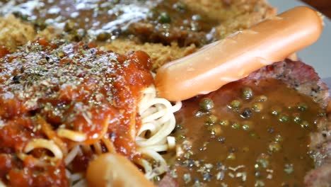 close up footage of combo steak included beef, fried fish and sausages topped with fresh pepper gravy and spaghetti red sauce