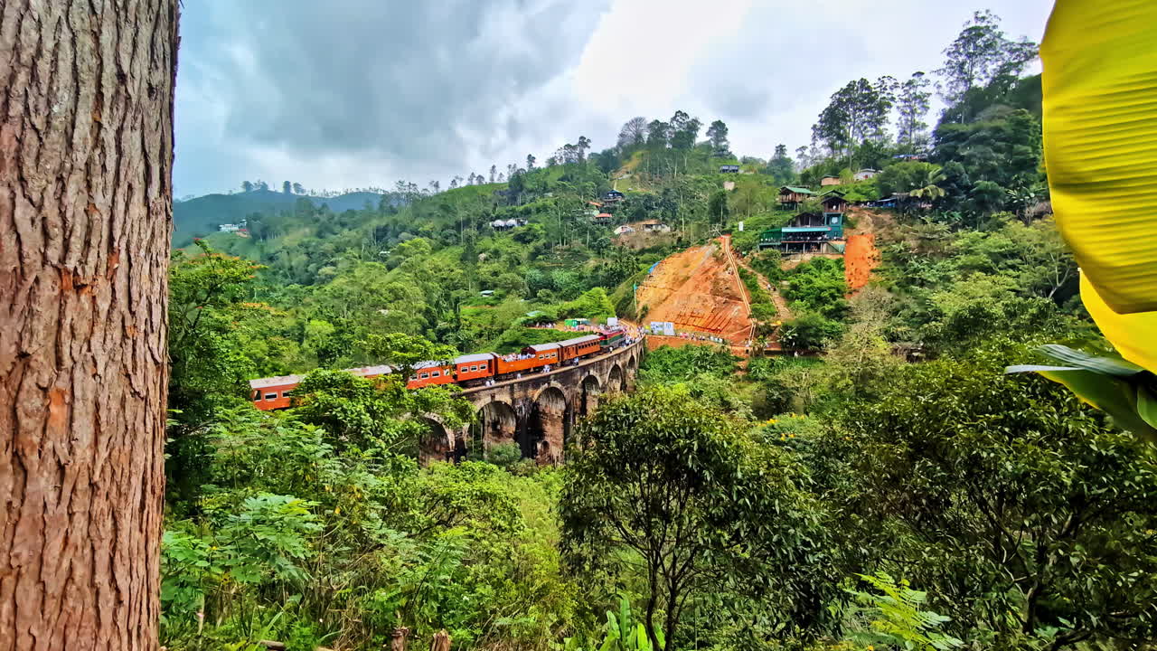 Orange Train Crossing the Historic Nine Arch Bridge in Lush Sri Lankan Mountains