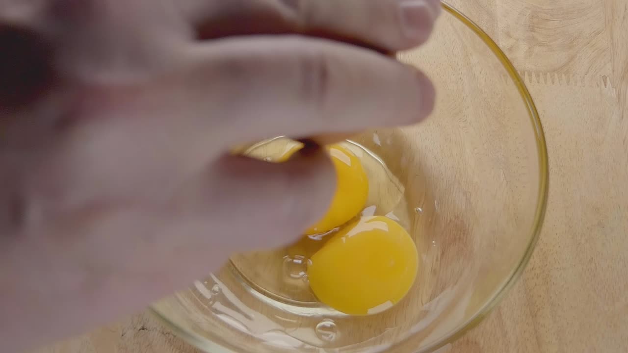 Slow Motion Shot of Eggs Being Cracked into a Glass Bowl in a Home Kitchen