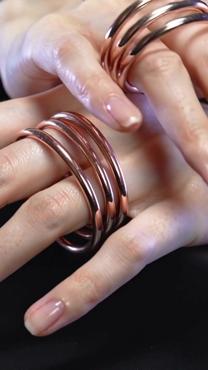 Video verticale: Mani che si muovono, con la mano superiore che sistema anelli di bobine di rame su un panno scuro.