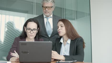 three caucasian partners discussing project on laptop