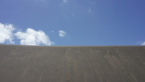 Aerial-shot-along-high-sand-dunes-of-Bethell-Beach-in-Auckland,-NZ