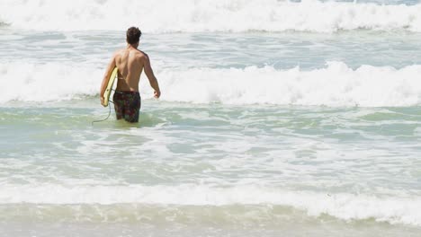 male surfer walking with surfboard in the sea at beach 4k