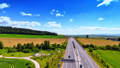 open road through greenery. a highway runs through a vibrant green landscape under a bright blue sky with scattered clouds during daylight