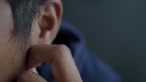 close up of a man's face and ear with a finger touching his cheek