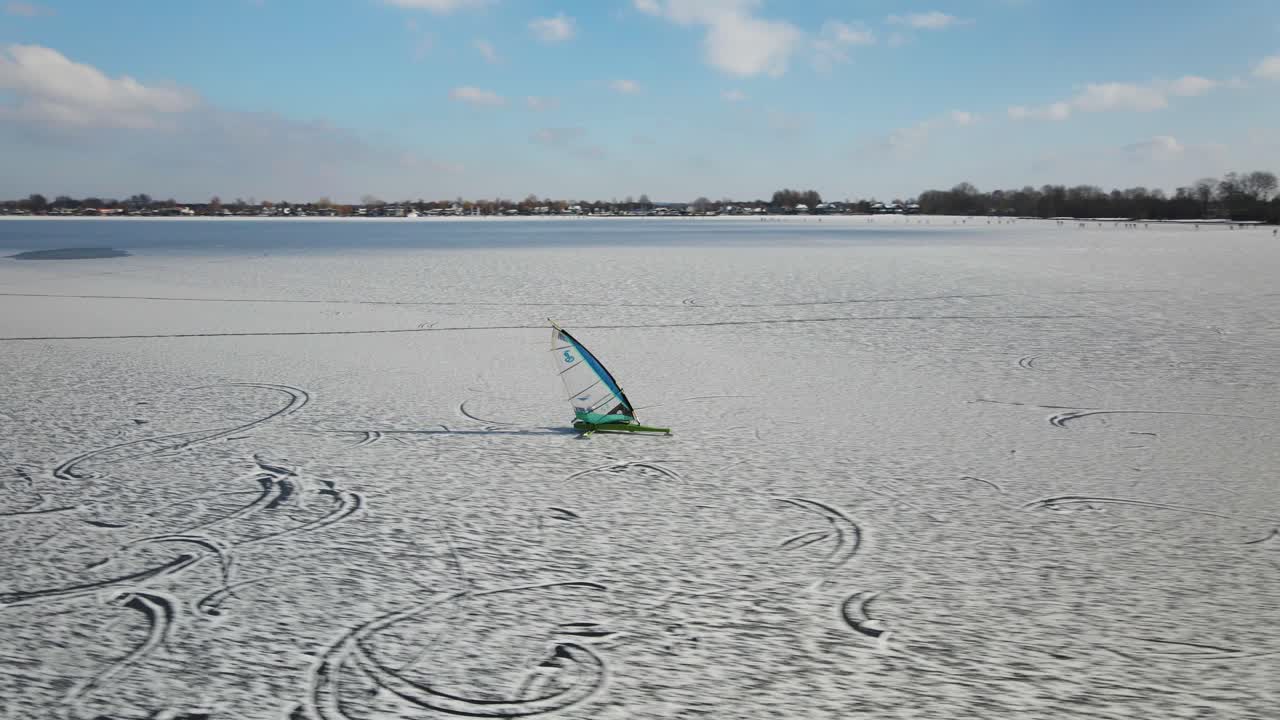 겨울 동안 네덜란드의 눈 덮인 얼음 호수에서 서핑하는 얼음 선원 - 공중 트랙 샷