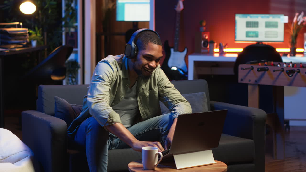 Vertical Video African American guy working on laptop celebrating achievement under neon lights
