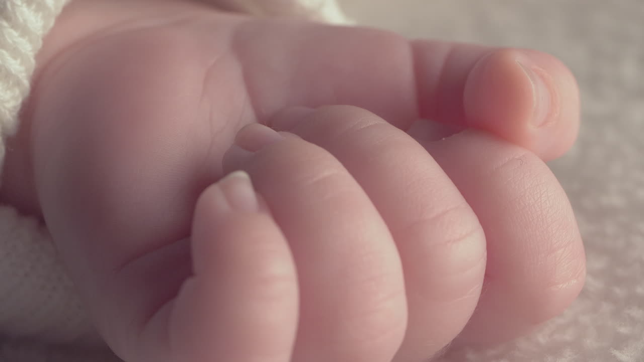 Beautiful Baby newborn is lying in bed and shows hands and feet, mother fandles with baby and covers her up with a cosy coverlet,4k 60p Apple ProRes422, with external Atoms recorder-11