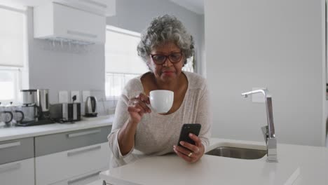 una mujer afroamericana mayor que pasa el tiempo en casa sosteniendo una taza. distanciamiento social en cuarentena