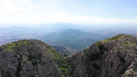 Drohnenaufnahme,-Die-Sich-Vorwärts-Zwischen-Den-Beiden-Gipfeln-Bewegt,-Um-Den-Epischen-Und-Dramatischen-Blick-Auf-Die-Landschaft-Unten-Im-Zaghouan-Tal-In-Tunesien-Freizugeben