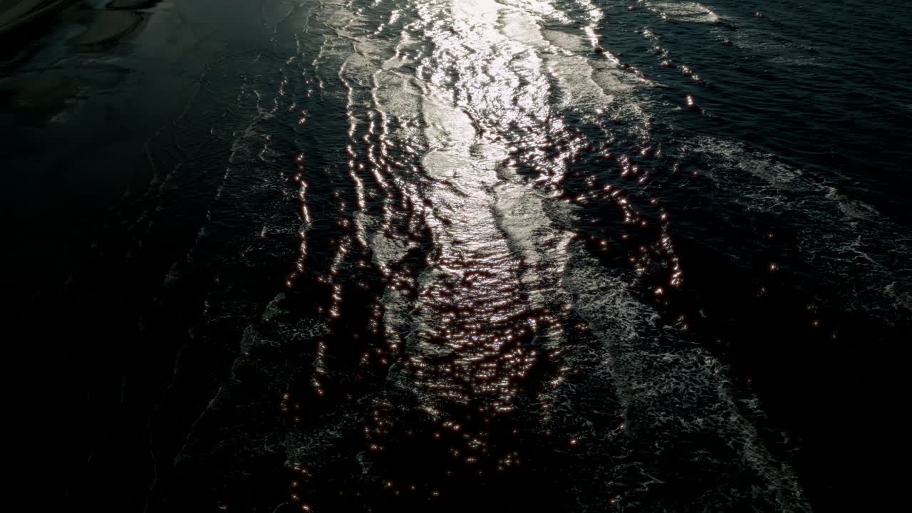 el agua negra oscura con un misterioso patrón de olas y reflejos de luz crea una escena enigmática y cautivadora, destacando la belleza natural del mar.