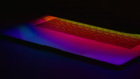 A-modern-laptop-with-the-keyboard-illuminated-under-a-multicolored-neon-glow