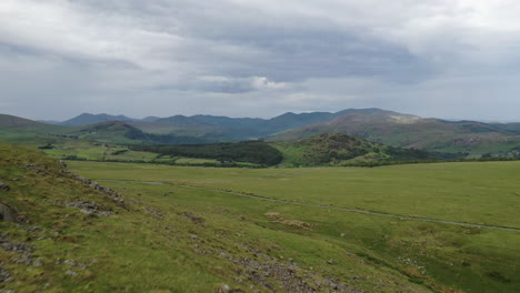 Aerial-shot-moving-backwards-along-the-side-on-a-hill-in-the-English-Lake-District,-summers-day