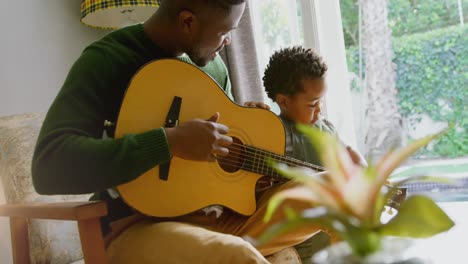 Animation-of-light-flashing-over-african-american-father-and-son-playing-guitar