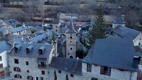 Casas-Históricas-De-Piedra-De-Anciles-Enclavadas-En-El-Pirineo-Aragonés,-Con-Picos-Nevados-De-España-Al-Fondo---Aéreo