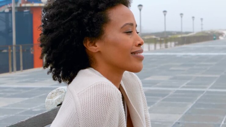 Thoughtful young African american woman sitting on bench at promenade 4k
