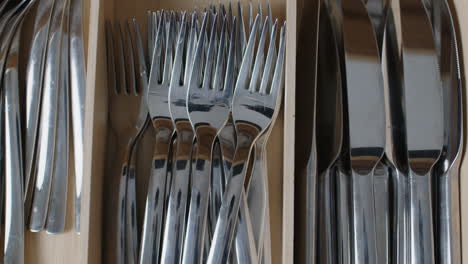 top shot of an open kitchen drawer, putting two forks into the drawer