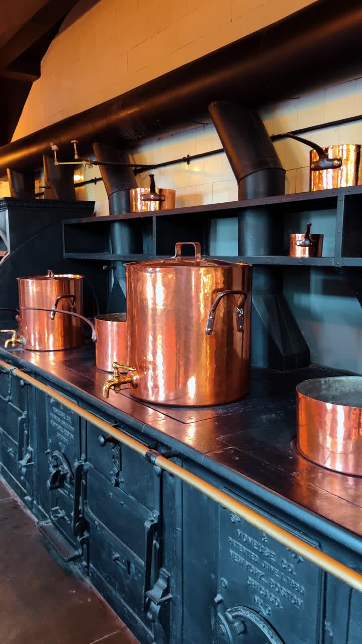 Large antique cast iron stove with copper stock pots. Professional vintage black cooking range with polished copper pots in a grand estate kitchen