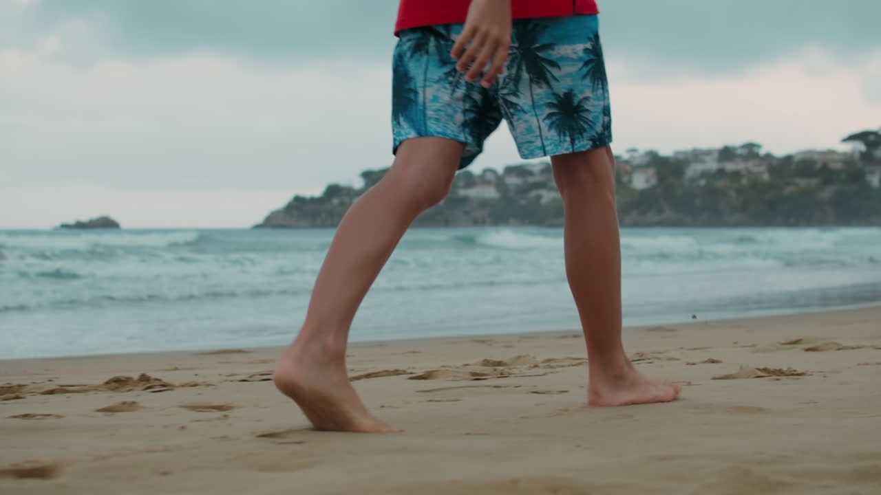 niño irreconocible pasando el verano en la orilla del mar. hombre desconocido caminando en la orilla del mar.