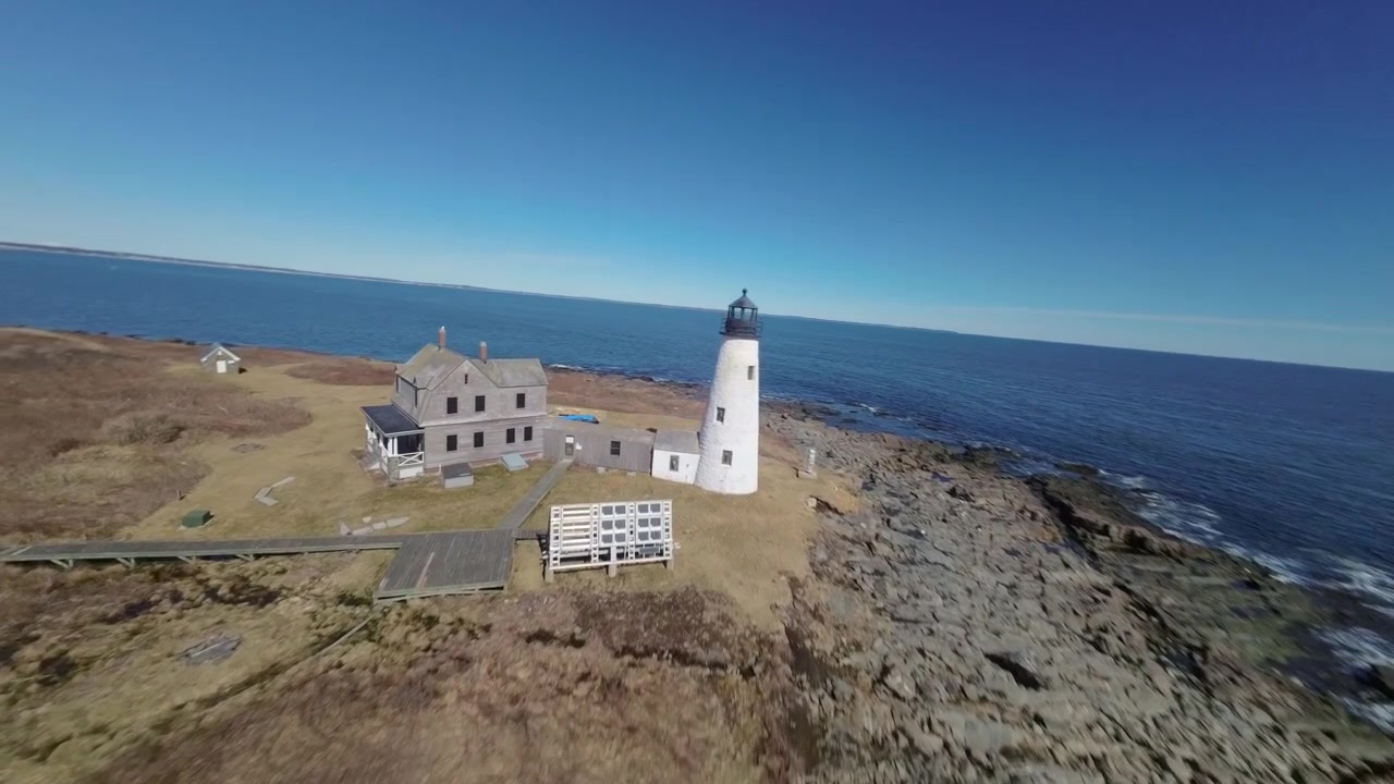 FPV-droneopptak flyr rundt ikonisk hvitt fyrtårn på Wood Island i Saco Bay, Maine, med det enorme havet som en fantastisk bakgrunn.