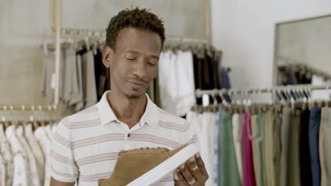 thin african american guy examining shoe before purchase.