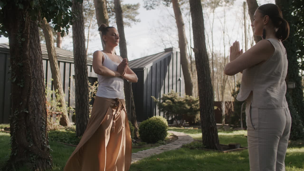 Two women practicing yoga in a beautiful garden